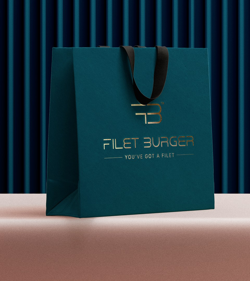 Busta di carta verde petrolio con monogramma FB, scritta Filet Burger e claim You've got a filet in oro