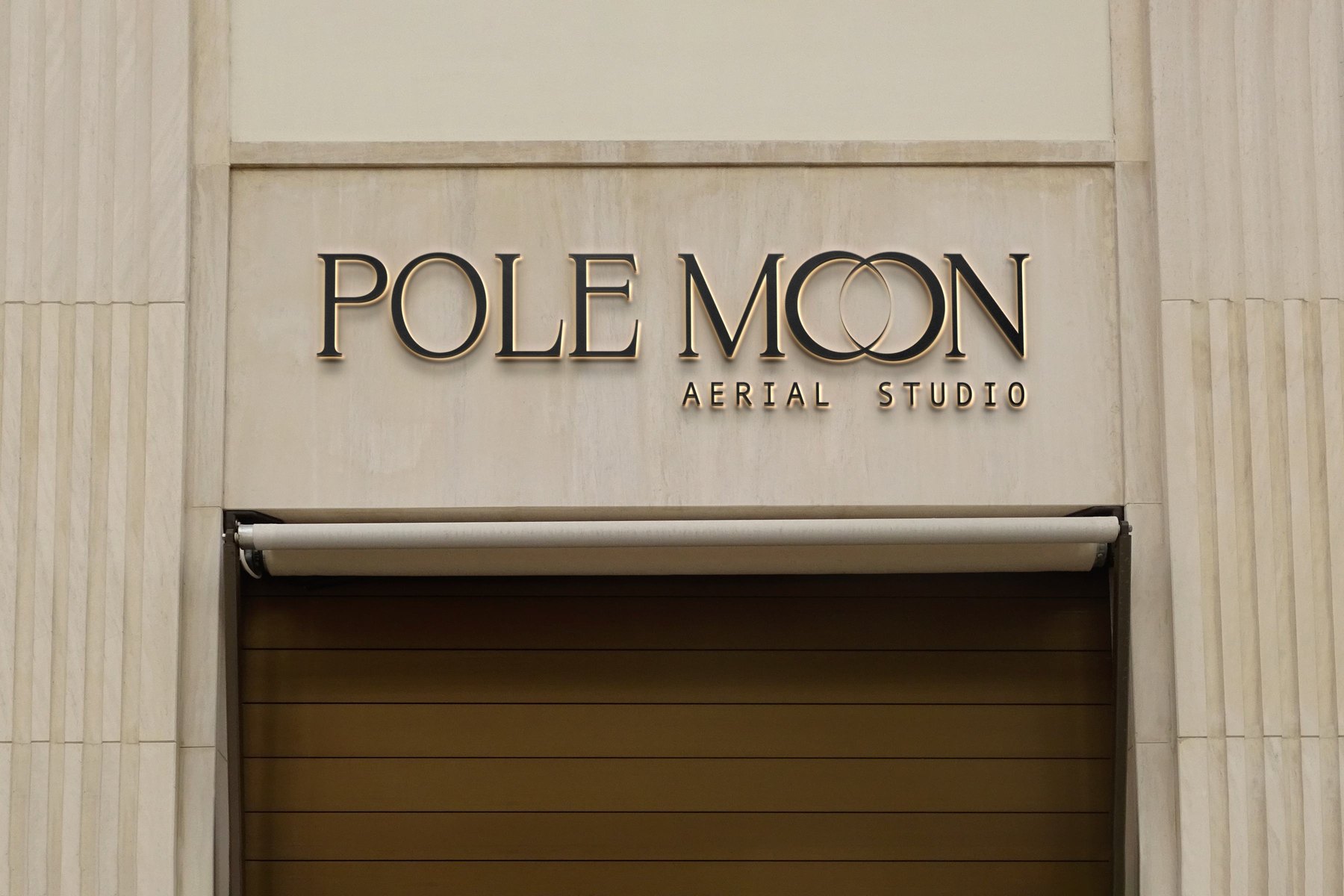 Insegna luminosa Pole Moon Aerial Studio su facciata in pietra chiara